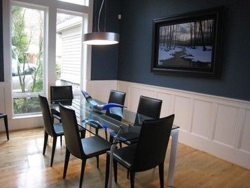 a dining room table with black chairs in front of a large window and wood flooring