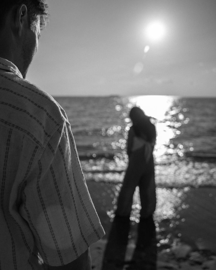 a man standing on top of a beach next to the ocean