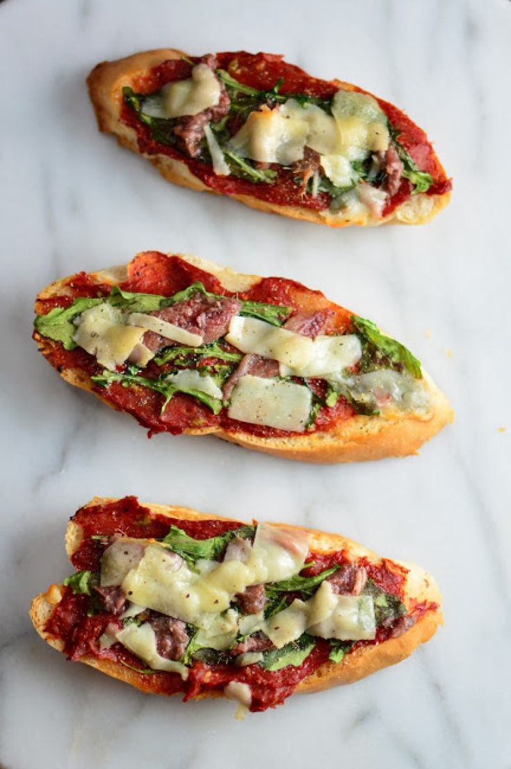 three pieces of bread with different toppings on them sitting on a marble counter top