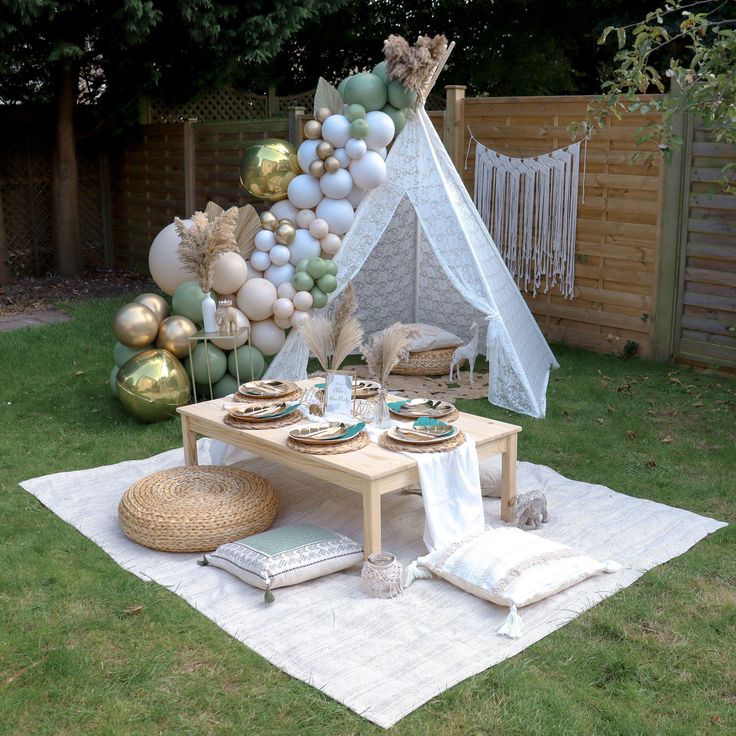 a table set up for a party with balloons in the back ground and a teepee tent