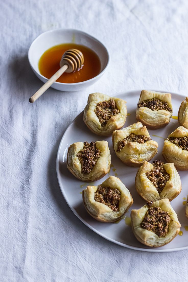 small pastries on a plate with honey in a bowl