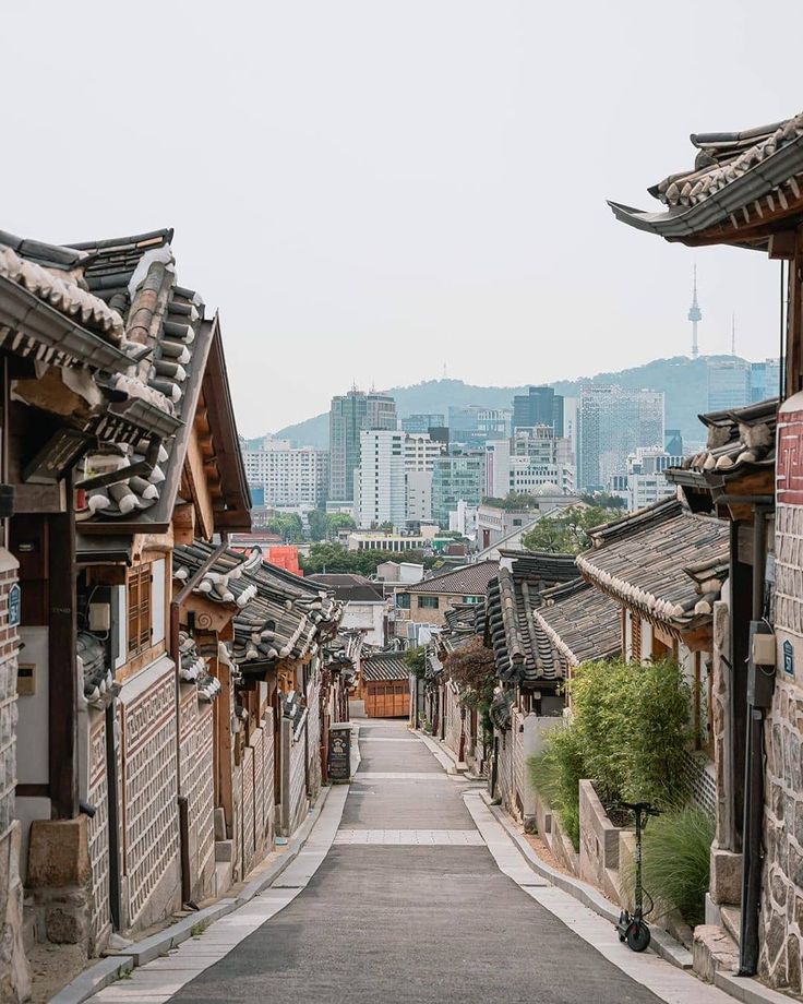 an empty street lined with old buildings and tall buildings in the distance are some mountains