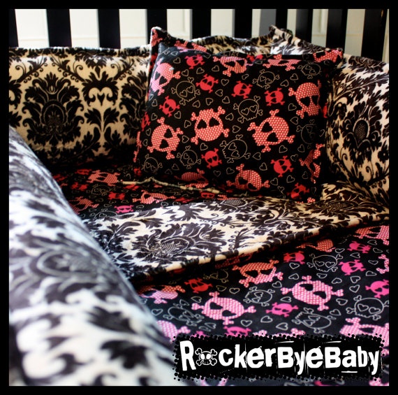 a black and pink bed with skulls on it's cover is in the crib