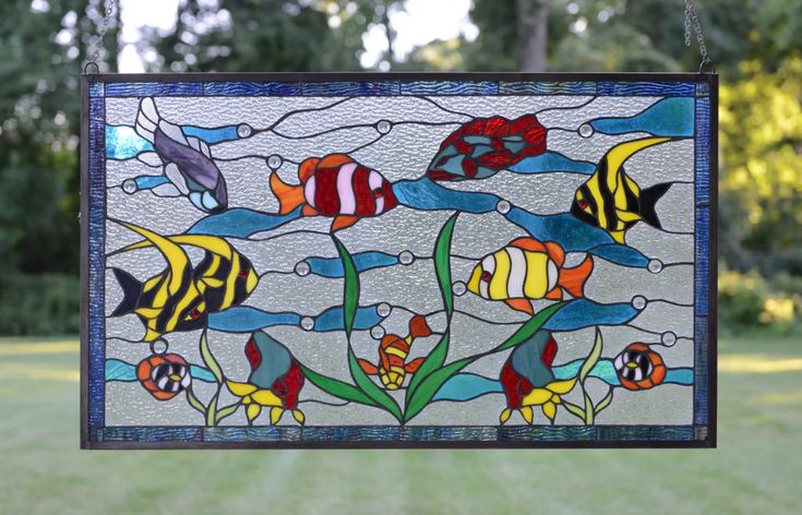 a stained glass window hanging in the air with fish and flowers on it's side