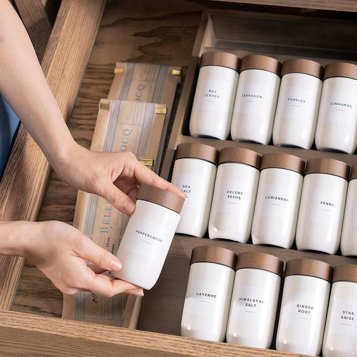 a person is holding a jar in front of many boxes with candles on them and one hand reaching for it