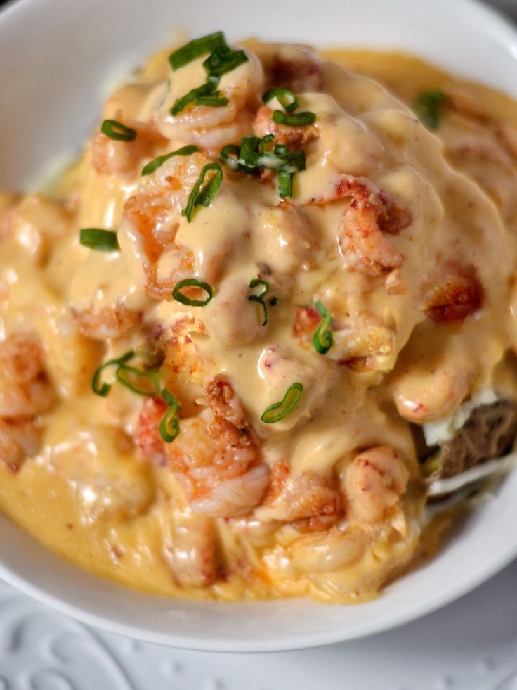 a white bowl filled with shrimp and grits covered in gravy on top of a table