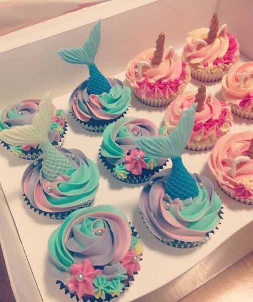 cupcakes decorated with pastel colors and mermaid tail decorations in a white box