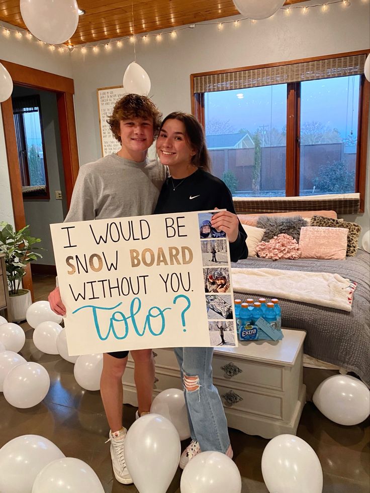 two people standing next to each other holding a sign that says i would be snowboard without you toto?