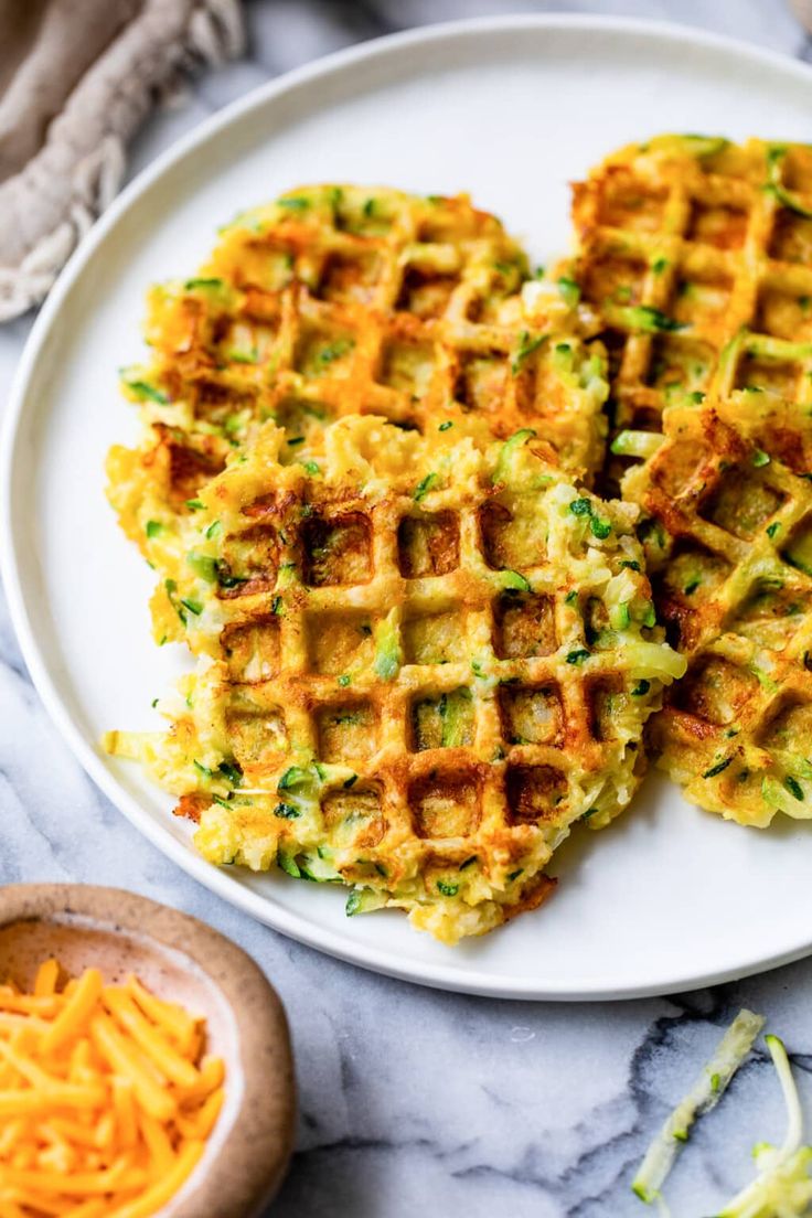 three waffles on a plate with shredded cheese