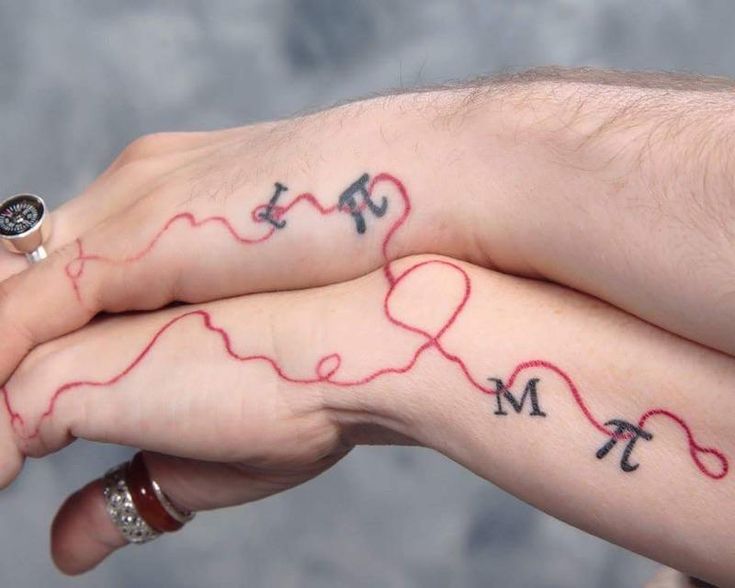 two people with tattoos on their hands holding each other