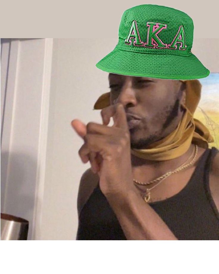 a man wearing a green hat with the word aka written on it and pointing to his finger