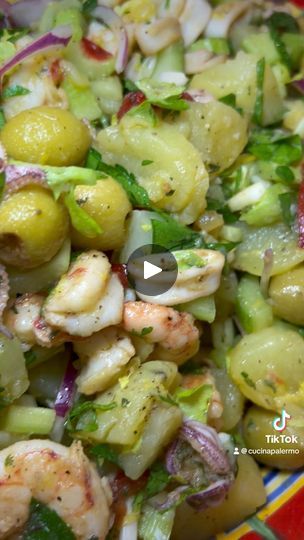 a colorful bowl filled with shrimp, olives and other vegetables on top of a table