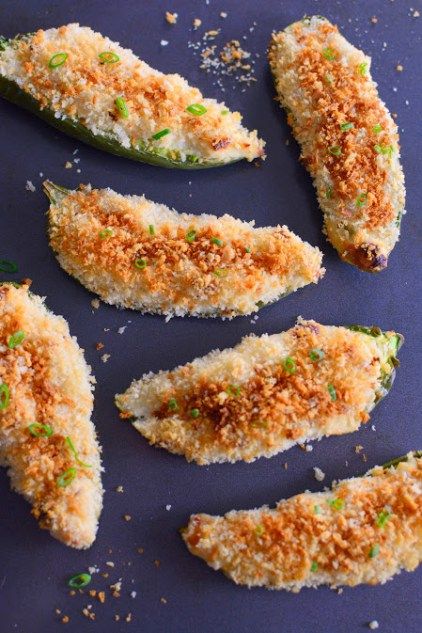 several pieces of fried food on a blue surface with parmesan and seasoning