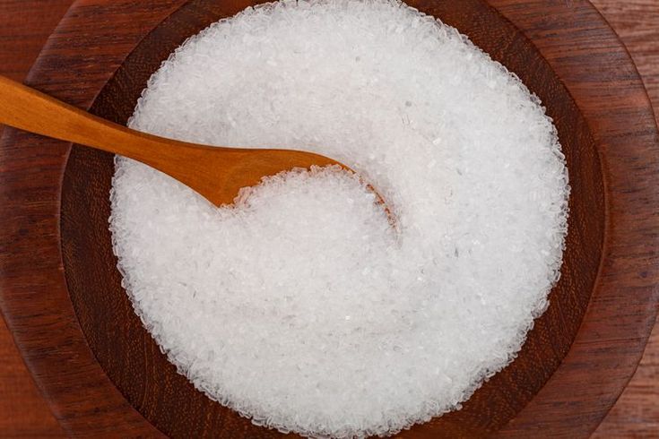 a wooden bowl filled with sugar and a wooden spoon