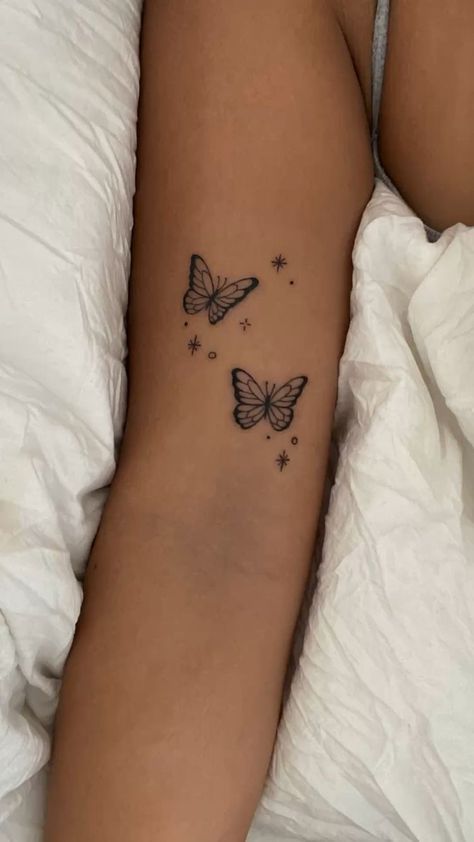 a woman's arm with two butterflies on it and stars in the sky above her