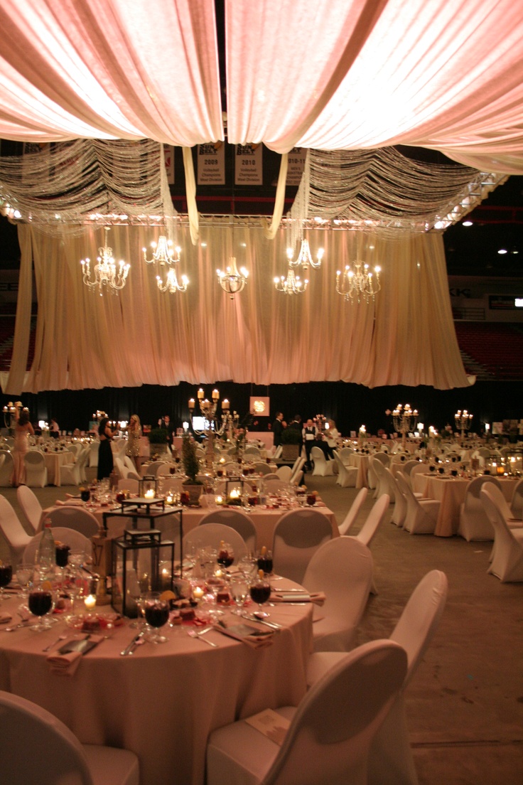 a banquet hall with tables and chairs covered in white draping