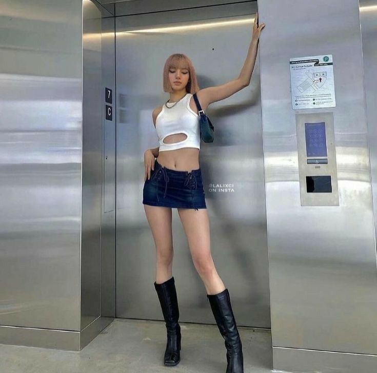 a woman standing in front of an elevator with her hand up to the door and wearing boots