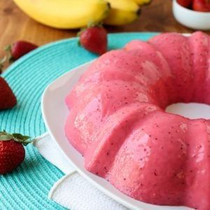 a bundt cake on a plate with strawberries and bananas in the background