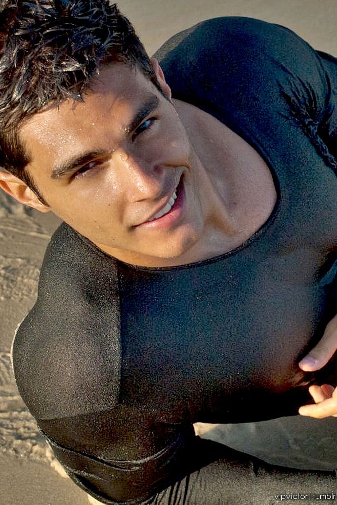 a man in a wet suit laying on the sand with his hands behind his back