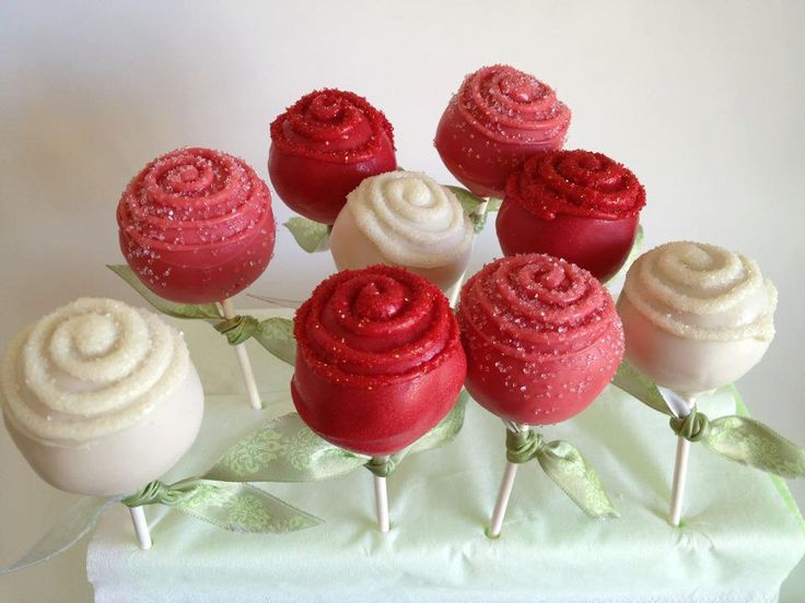 a bunch of red and white cake pops with sprinkles