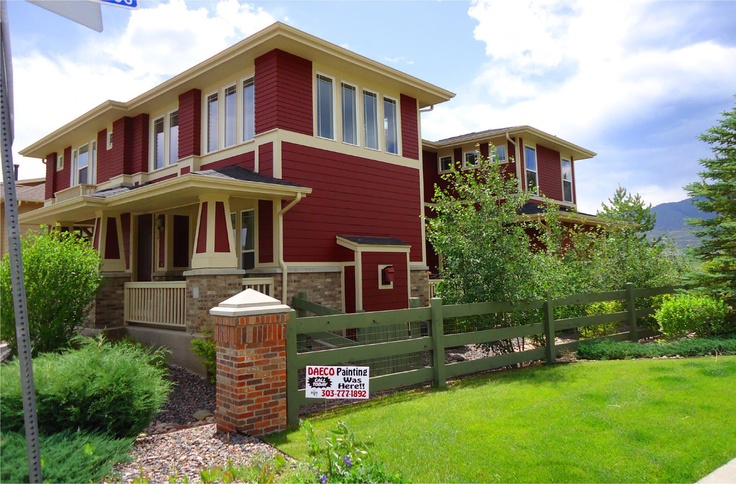 a red two story house with a for sale sign in front