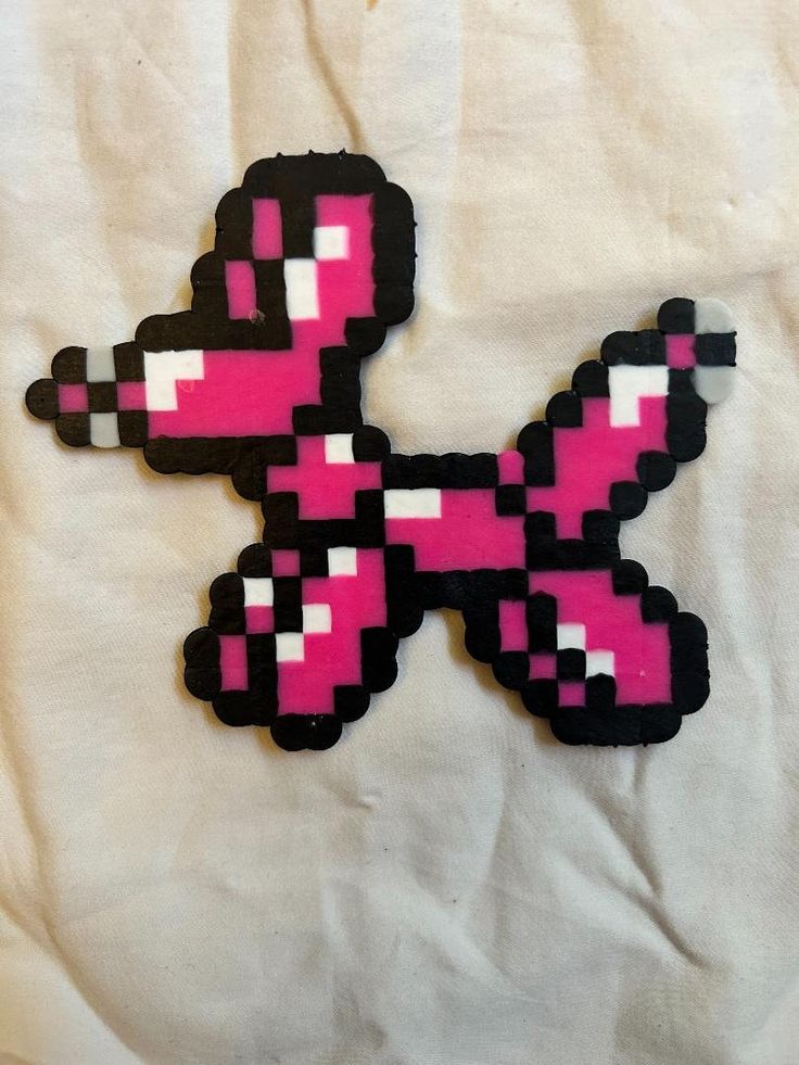 a pink and black pixel art piece sitting on top of a white sheet