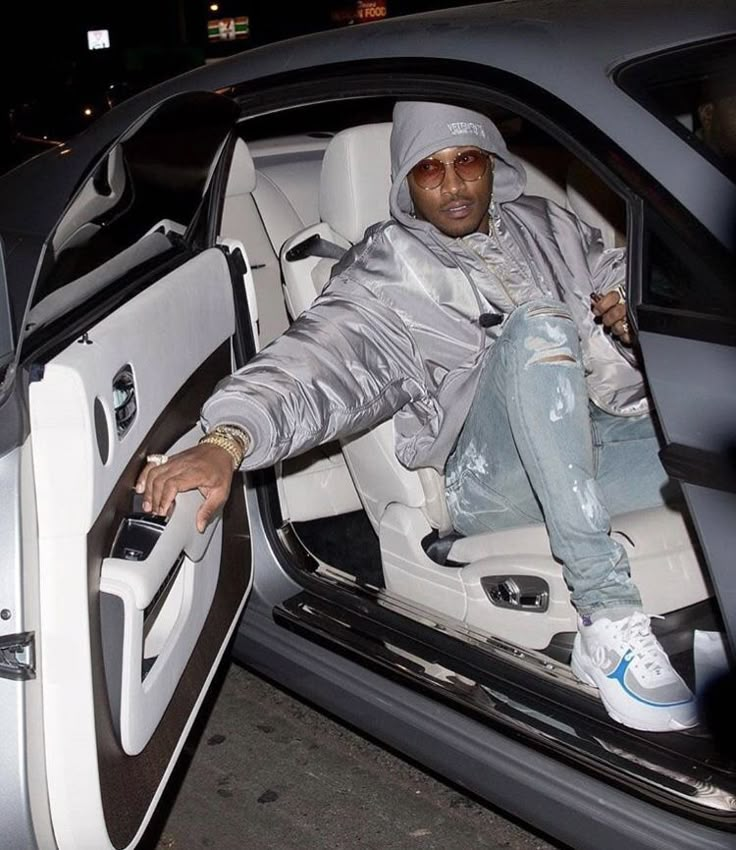 a man sitting in the driver's seat of a car with his foot on the door handle