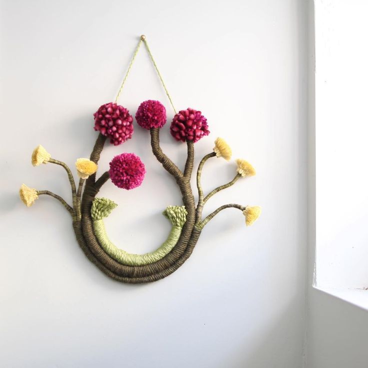 a decorative wall hanging with flowers and leaves on it's side, in the shape of a tree