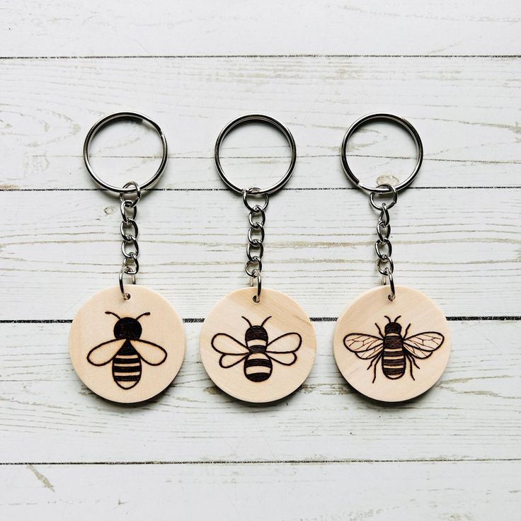 three wooden key chains with bees on them