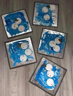 four snowmen made out of blue and white paper on the floor with silver foil