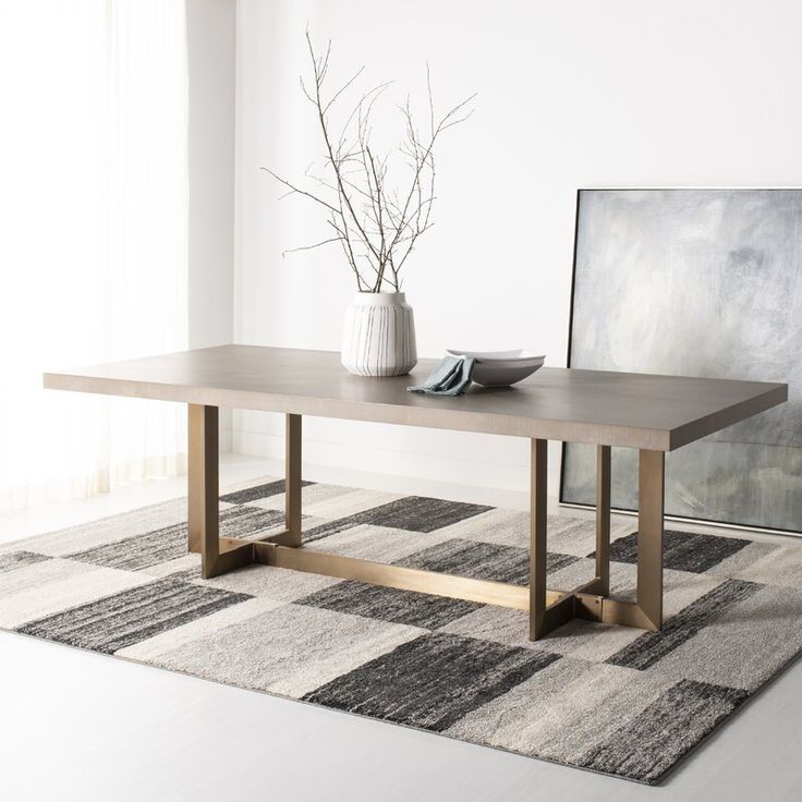 a wooden table sitting on top of a rug next to a vase filled with flowers