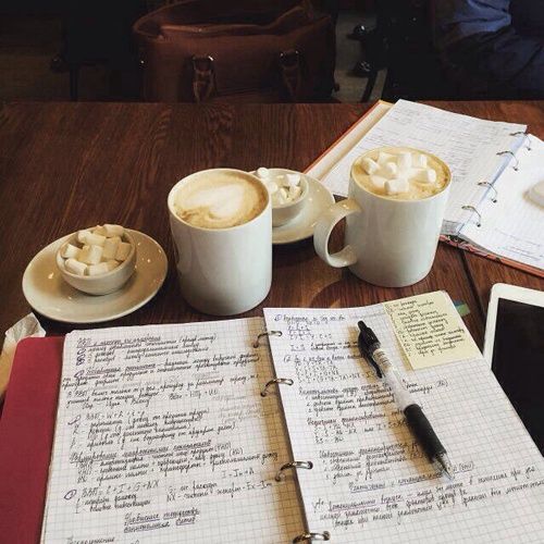 two cups of coffee sit on top of an open notebook