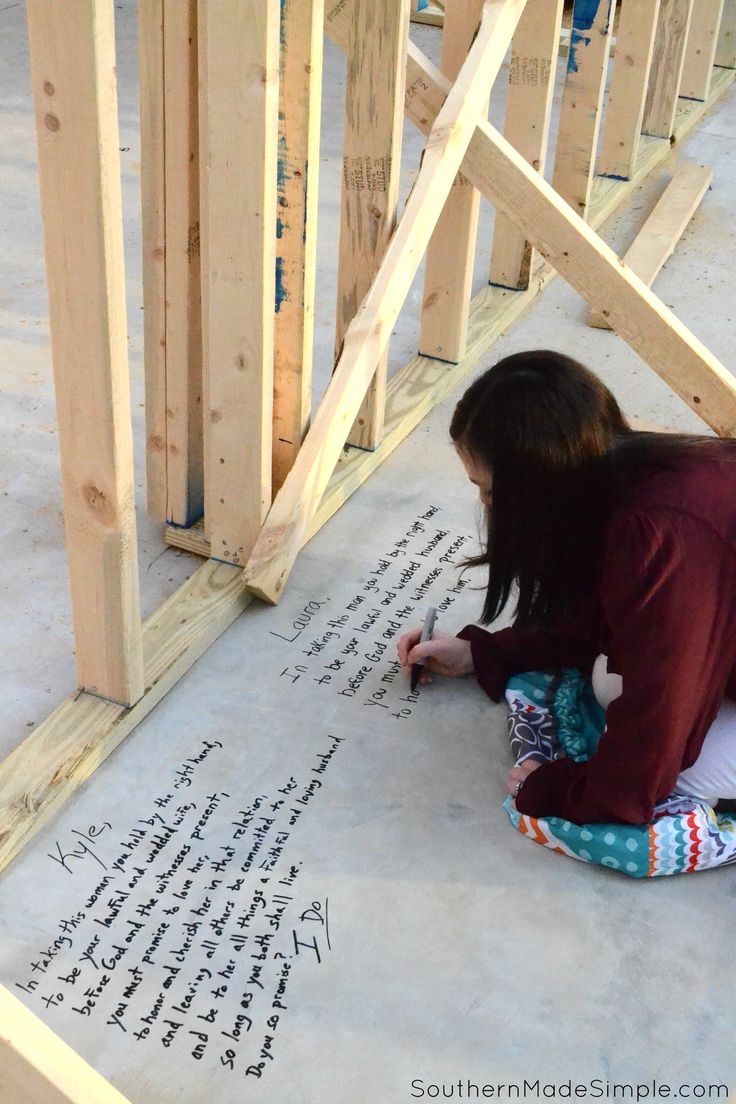 a girl is writing on the floor in front of some wooden framing