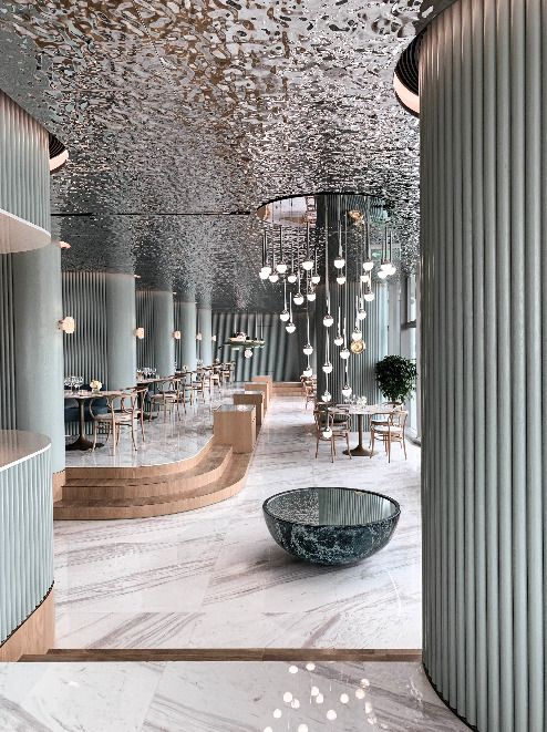 the interior of a modern restaurant with marble floors and walls, chandeliers hanging from the ceiling