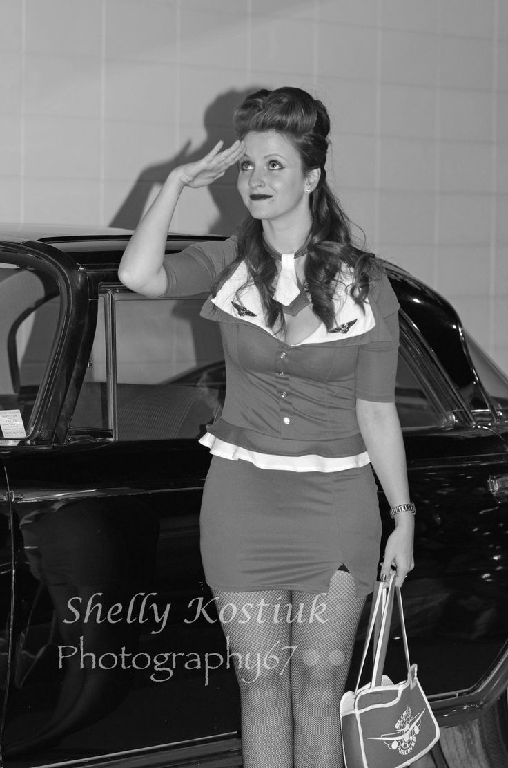 a woman standing next to a car holding a handbag