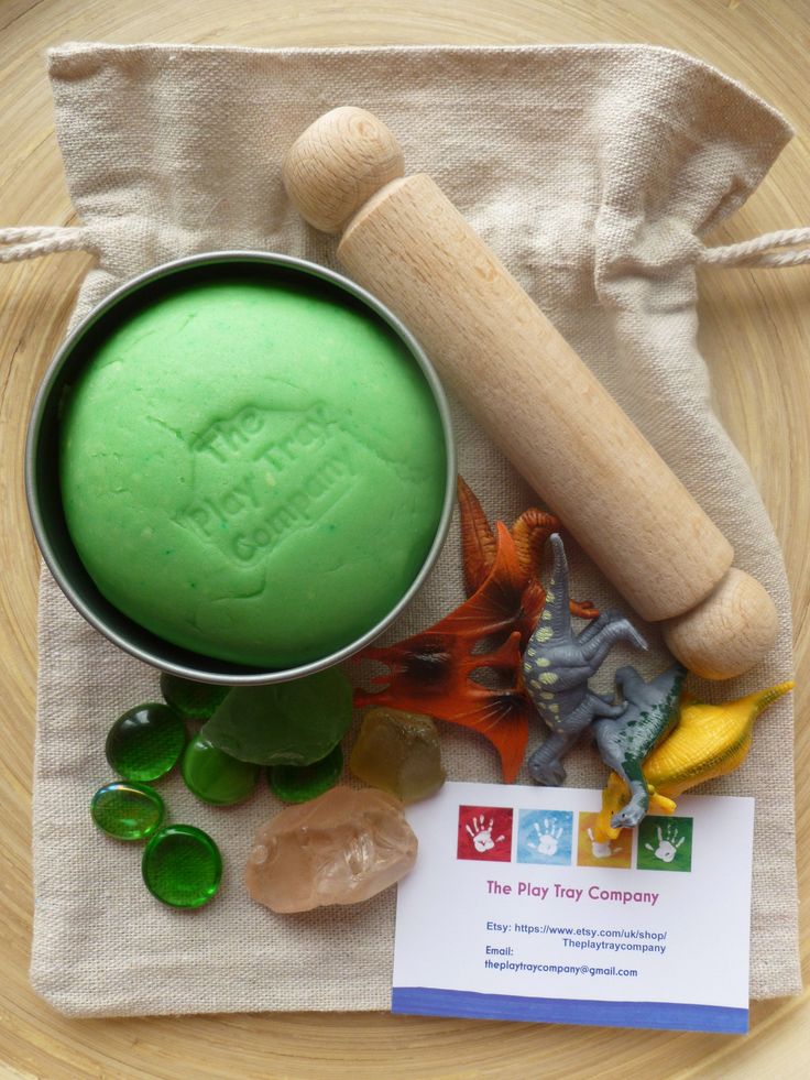 a green substance in a metal bowl next to some sea glass and a wooden rolling pin