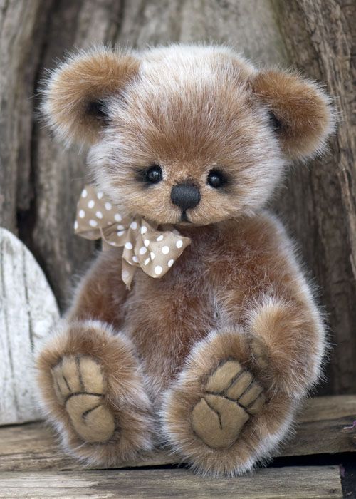 a brown teddy bear sitting on top of a wooden table