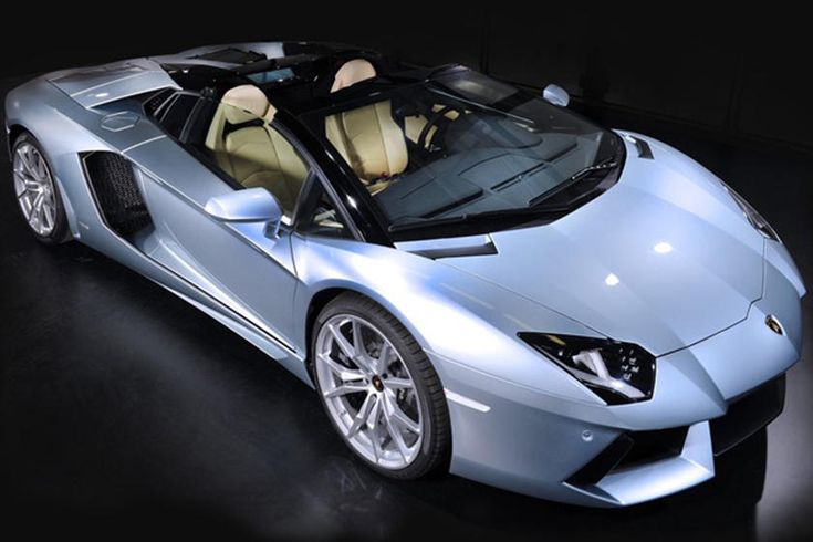 a silver sports car is parked in a dark room with its hood up and the top down