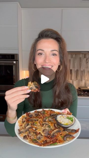 a woman holding a plate with food on it in front of her face and smiling at the camera