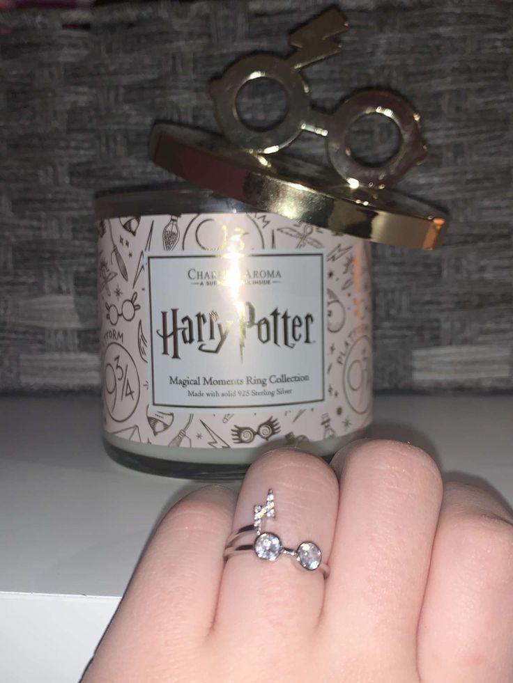 someone is holding their engagement ring in front of a harry potter jar with scissors on it