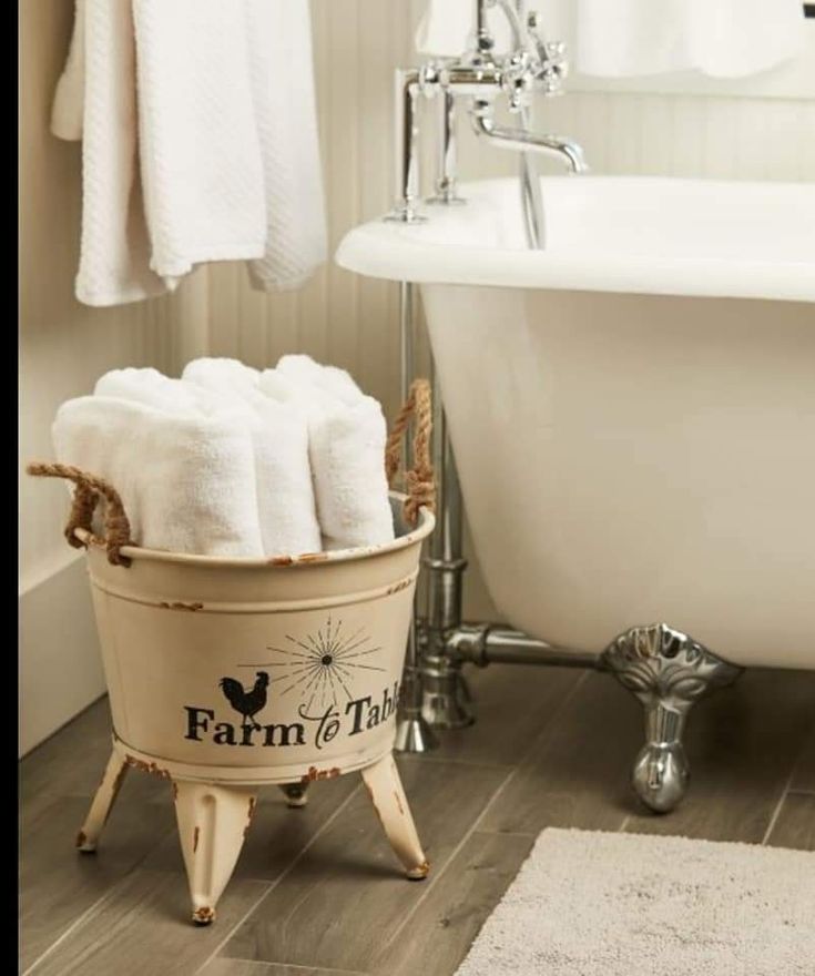 a bath tub with towels in it next to a rug and towel rack on the floor