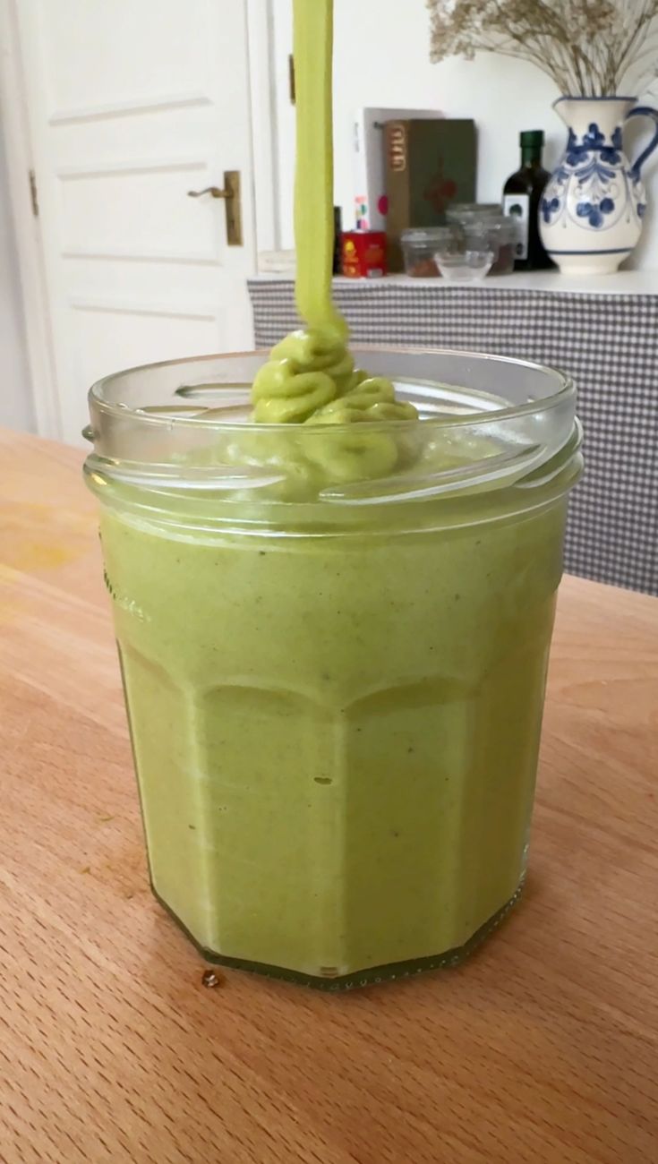 a jar filled with green liquid sitting on top of a wooden table