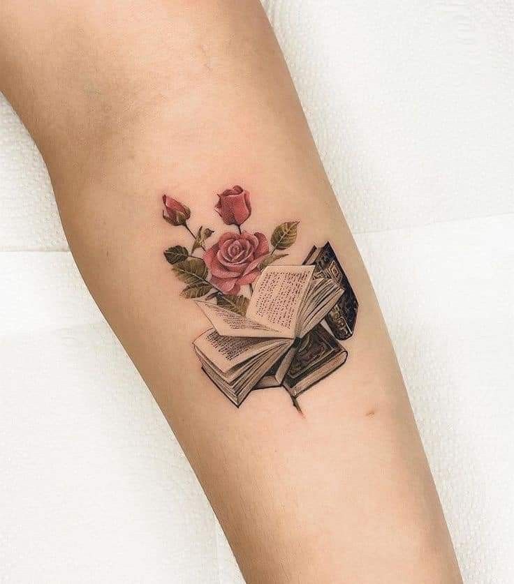 a rose and book tattoo on the arm