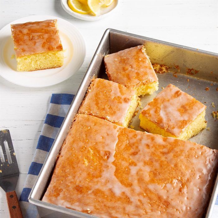 a pan filled with lemon cake next to a plate and fork on a table top