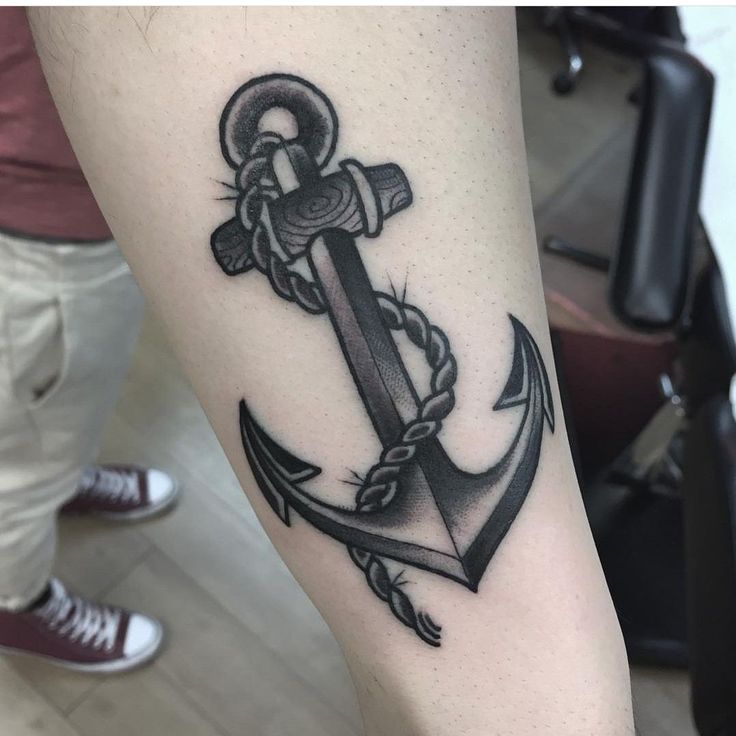 a black and white anchor tattoo on the right arm, with a rope around it