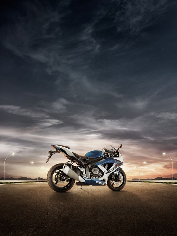 a blue motorcycle parked on the side of a road at night with clouds in the sky