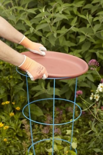 a person in white gloves and orange socks is holding a pink plate on a blue stand