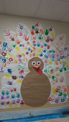 a turkey made out of handprints on a bulletin board in a school hallway