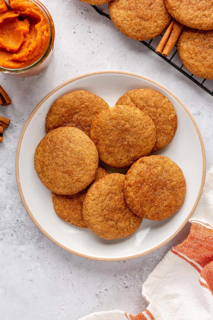 some cookies are on a white plate next to cinnamon sticks