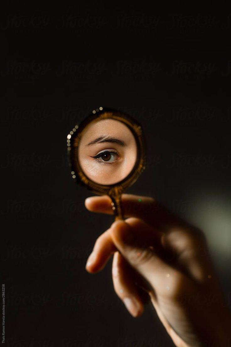 a woman looking through a magnifying glass at her face by jovan rijek for stocksy photography